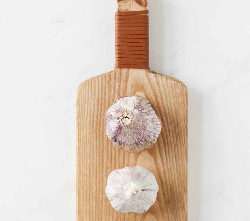 cutting board with garlic bulbs on marble table