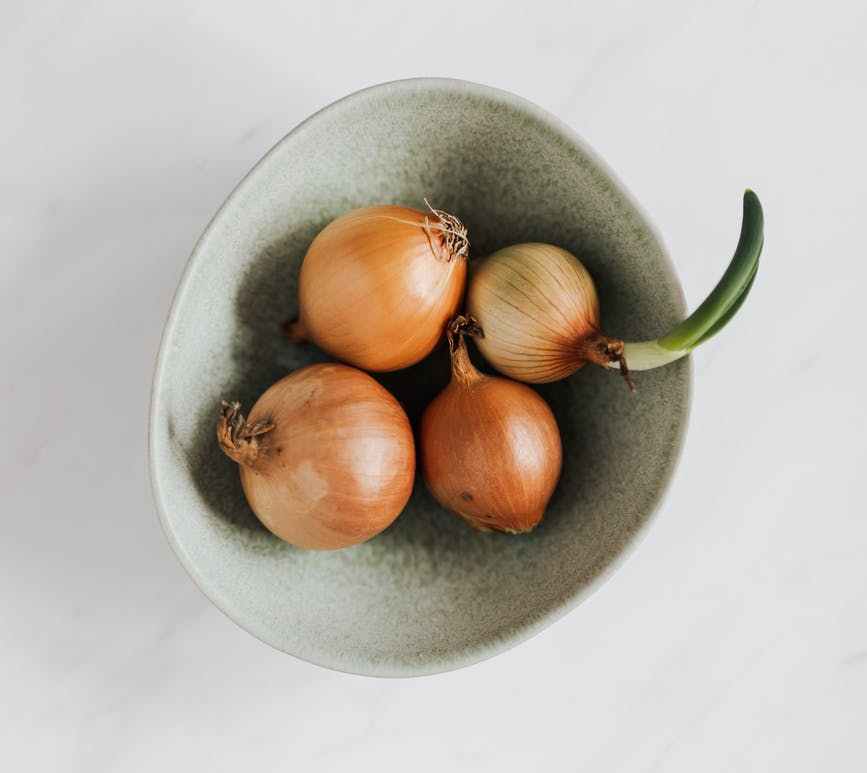 bowl with fresh onions on marble table